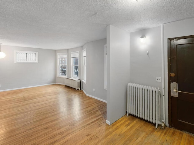 unfurnished room with radiator heating unit, light hardwood / wood-style floors, and a textured ceiling