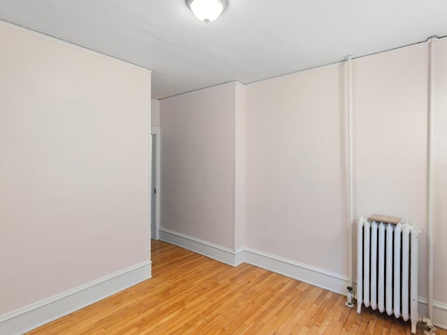 unfurnished room featuring wood-type flooring and radiator