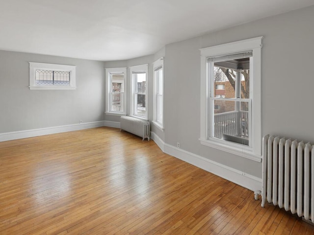 spare room featuring plenty of natural light, radiator, and light hardwood / wood-style floors