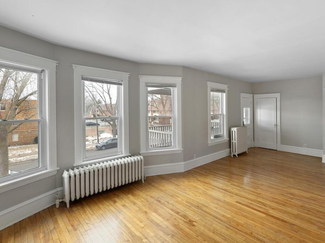 spare room featuring radiator and light hardwood / wood-style floors