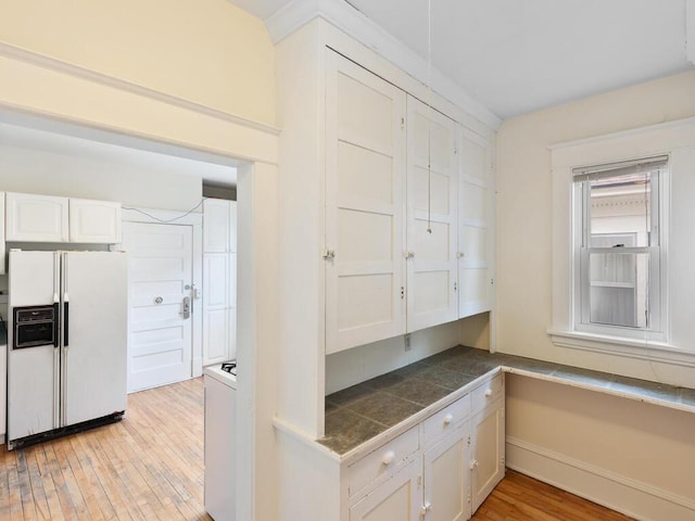 kitchen with white cabinetry, light wood-type flooring, and white fridge with ice dispenser