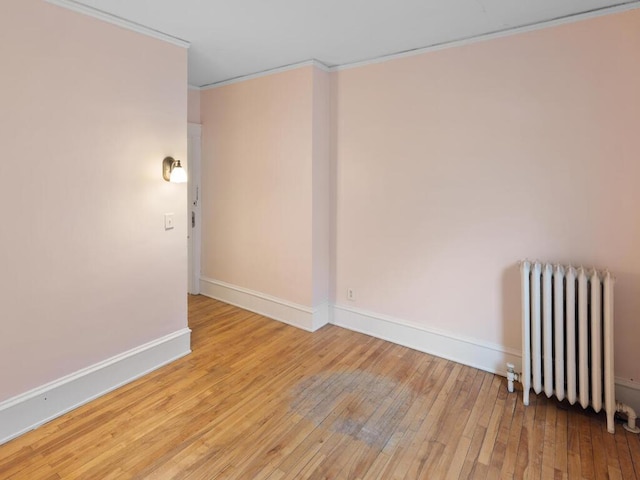 unfurnished room featuring ornamental molding, radiator heating unit, and light wood-type flooring