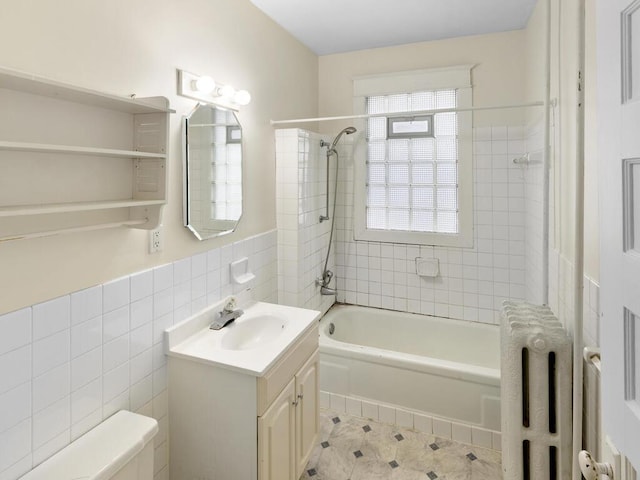 full bathroom with radiator, tile walls, tiled shower / bath combo, vanity, and toilet