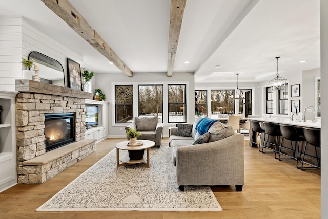 living room featuring beam ceiling, a fireplace, and light hardwood / wood-style flooring