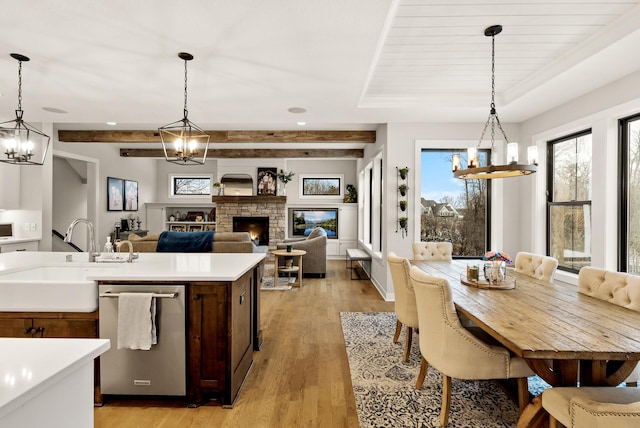 kitchen featuring sink, hanging light fixtures, light hardwood / wood-style flooring, dishwasher, and a notable chandelier