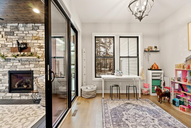 entryway featuring an inviting chandelier, a stone fireplace, and light hardwood / wood-style floors