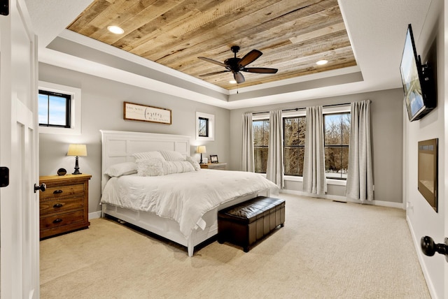 carpeted bedroom with a raised ceiling, ceiling fan, wood ceiling, and multiple windows