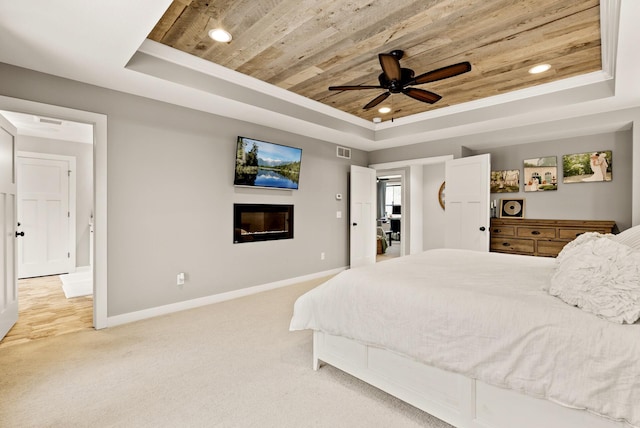 carpeted bedroom with a raised ceiling, ceiling fan, and wood ceiling