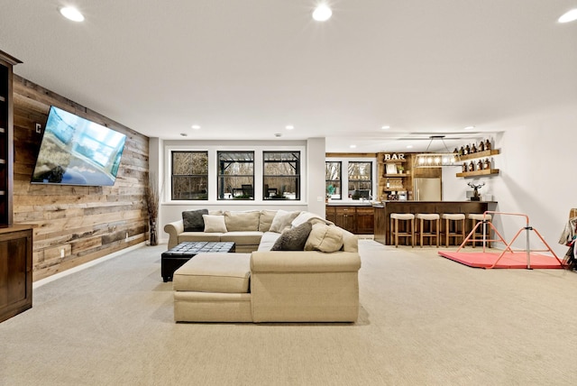 living room with bar area, light carpet, and wood walls