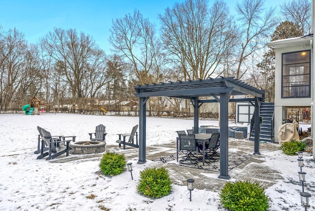 snow covered patio with a pergola, a fire pit, and a playground