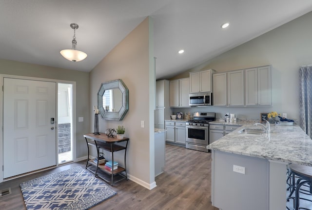 kitchen with kitchen peninsula, pendant lighting, appliances with stainless steel finishes, sink, and light stone counters