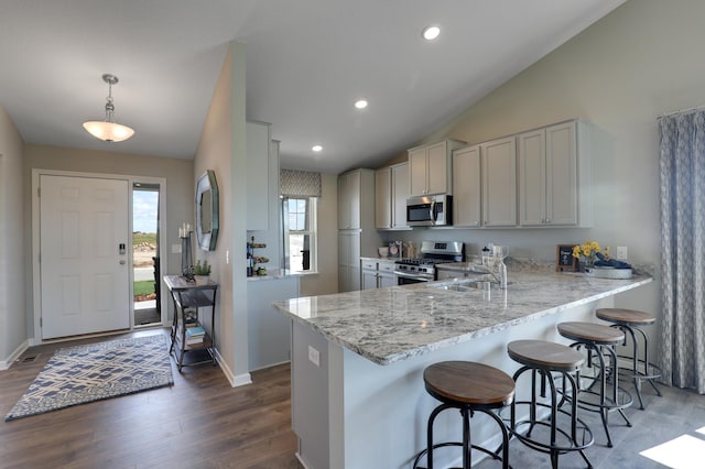 kitchen featuring appliances with stainless steel finishes, sink, kitchen peninsula, pendant lighting, and a breakfast bar