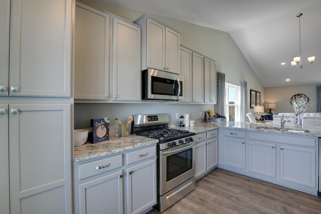 kitchen featuring vaulted ceiling, white cabinetry, stainless steel appliances, sink, and light wood-type flooring