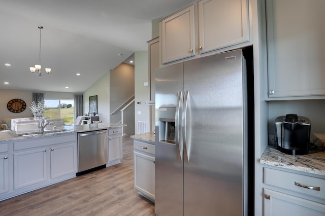 kitchen with light hardwood / wood-style flooring, sink, decorative light fixtures, lofted ceiling, and stainless steel appliances