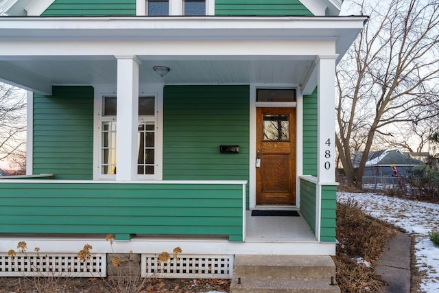 snow covered property entrance with a porch