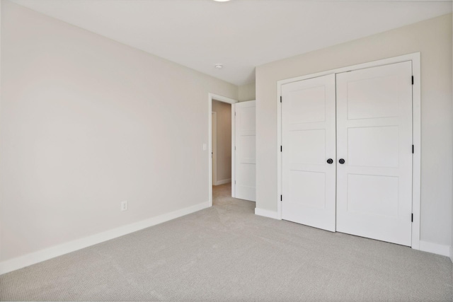 unfurnished bedroom featuring light colored carpet and a closet