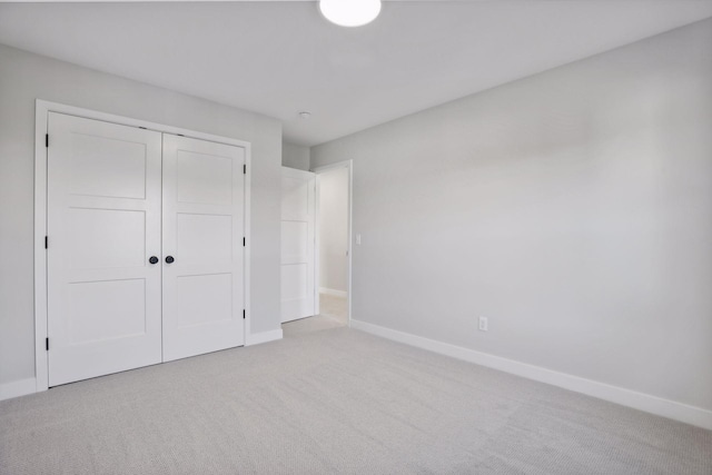 unfurnished bedroom with light carpet and a closet