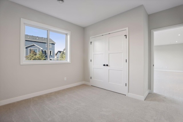 unfurnished bedroom with light colored carpet and a closet