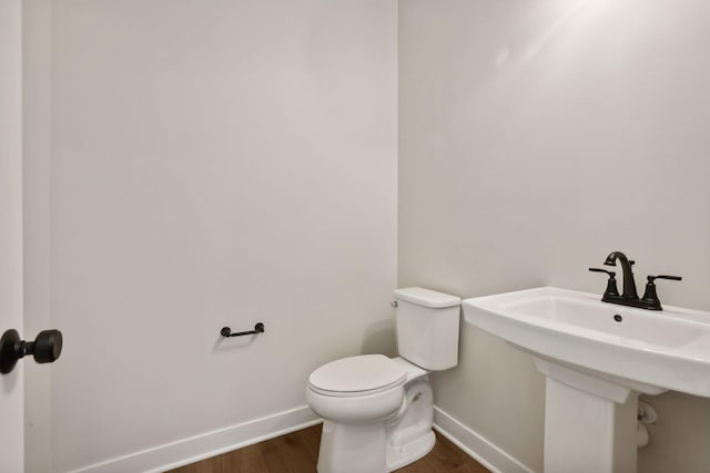 bathroom featuring wood-type flooring, toilet, and sink