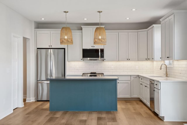 kitchen with sink, decorative light fixtures, a center island, appliances with stainless steel finishes, and white cabinets