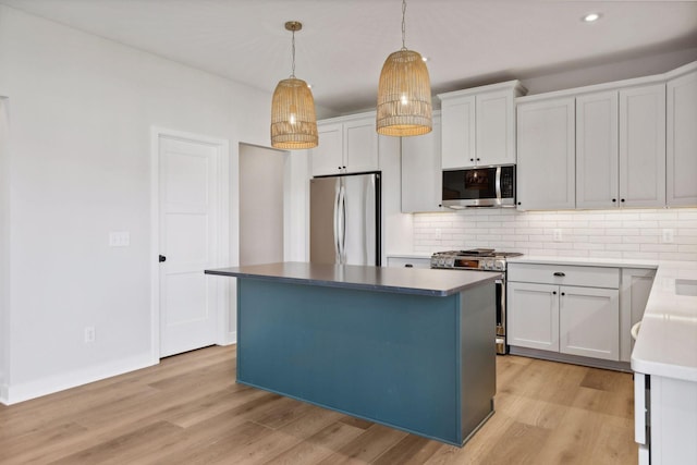 kitchen featuring hanging light fixtures, stainless steel appliances, tasteful backsplash, white cabinets, and a kitchen island