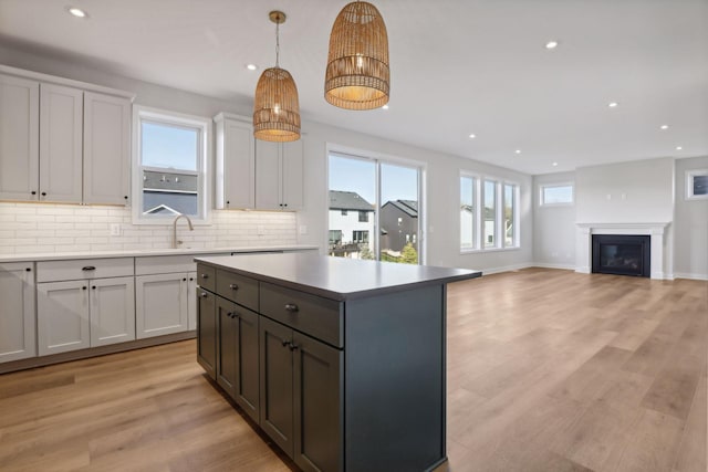 kitchen featuring white cabinetry, a center island, light hardwood / wood-style floors, and decorative light fixtures