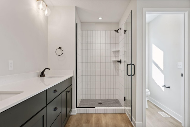 bathroom with vanity, hardwood / wood-style flooring, a shower with door, and toilet