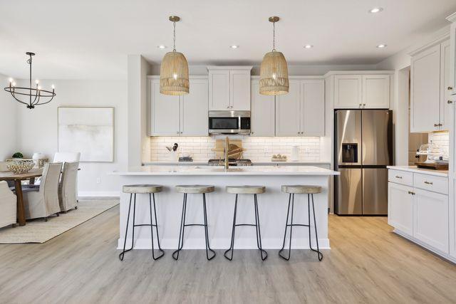 kitchen with white cabinetry, appliances with stainless steel finishes, pendant lighting, and a center island with sink