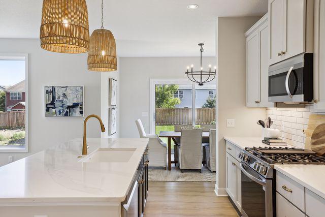 kitchen featuring sink, hanging light fixtures, a center island with sink, stainless steel appliances, and white cabinets