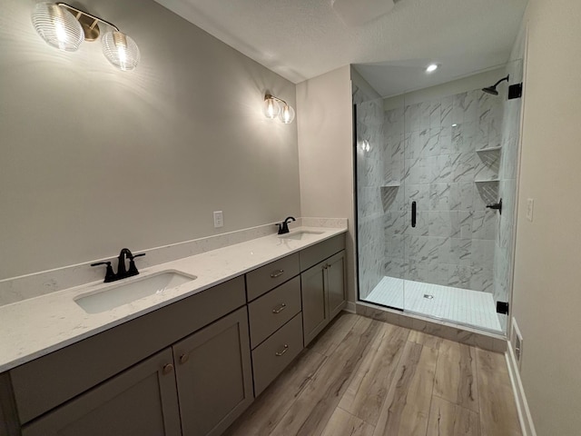 bathroom featuring vanity, hardwood / wood-style flooring, a shower with door, and a textured ceiling