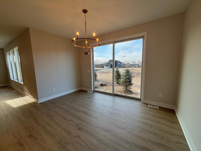 unfurnished dining area with hardwood / wood-style flooring and a notable chandelier