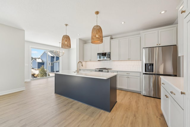 kitchen featuring white cabinetry, decorative light fixtures, a kitchen island with sink, and stainless steel appliances