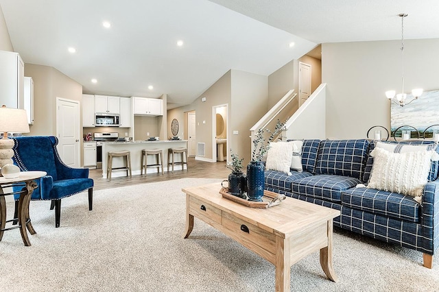 living room featuring an inviting chandelier, vaulted ceiling, and light wood-type flooring