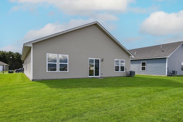 rear view of house with central AC and a yard