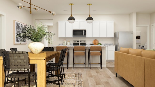 kitchen with stove, white cabinets, stainless steel microwave, freestanding refrigerator, and light wood-style flooring