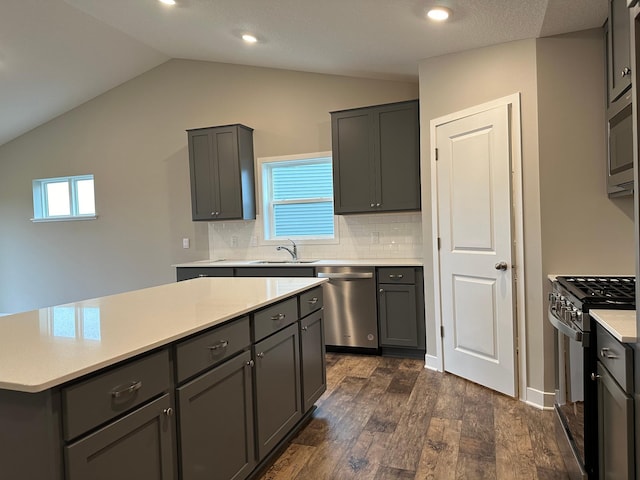 kitchen with lofted ceiling, gray cabinetry, stainless steel appliances, dark hardwood / wood-style floors, and a center island