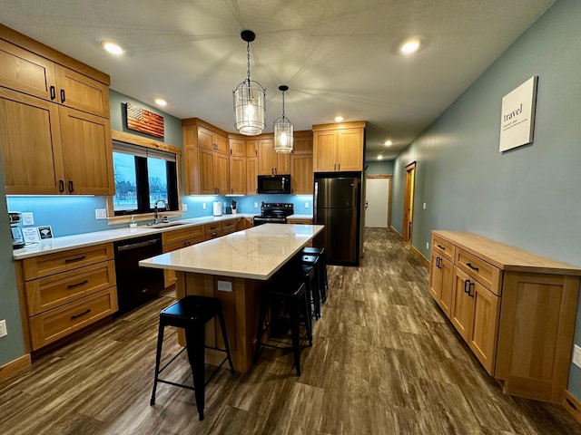 kitchen featuring sink, a kitchen breakfast bar, black appliances, a kitchen island, and decorative light fixtures