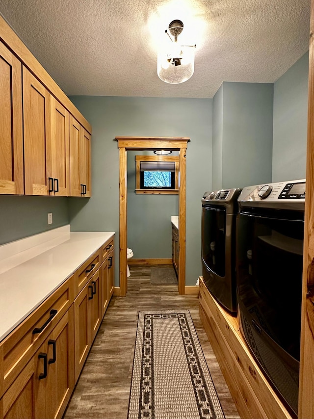 laundry room featuring separate washer and dryer, dark wood-type flooring, cabinets, and a textured ceiling