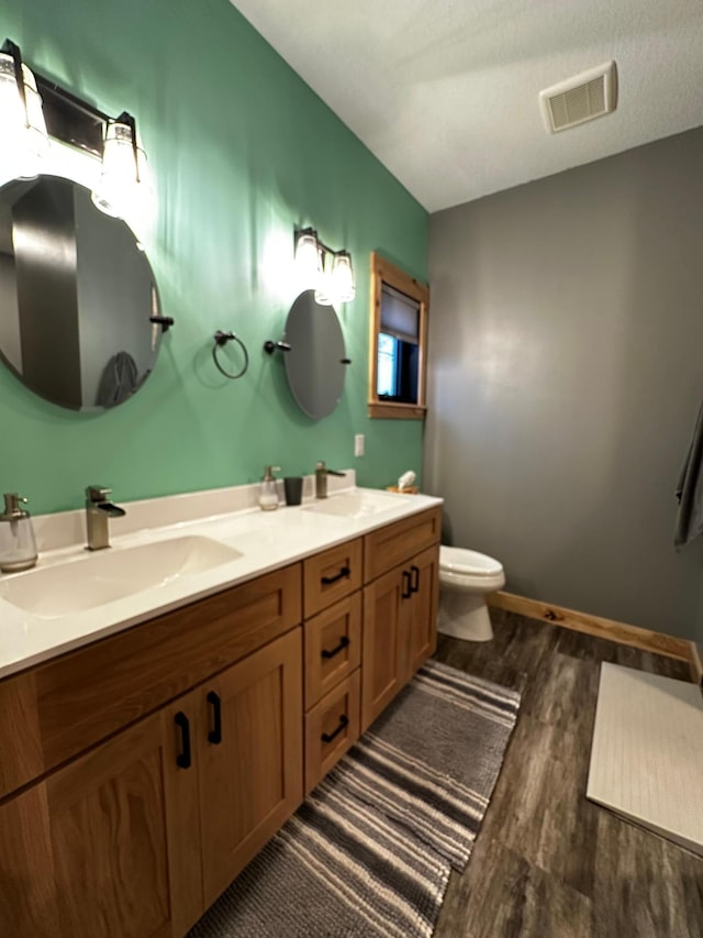 bathroom with hardwood / wood-style flooring, vanity, toilet, and a textured ceiling