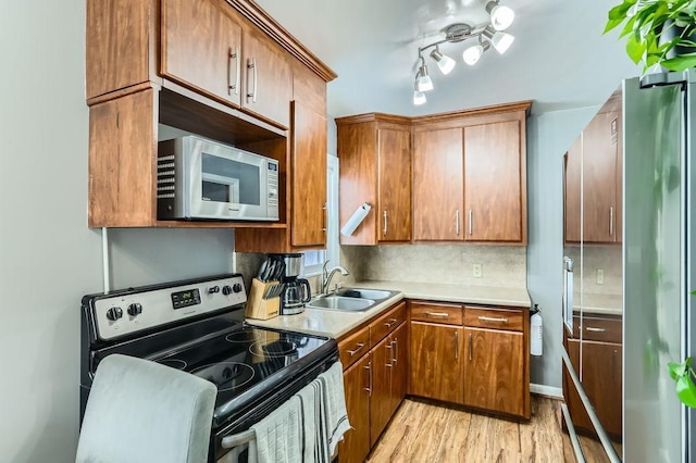 kitchen with stainless steel appliances, light hardwood / wood-style floors, sink, and backsplash