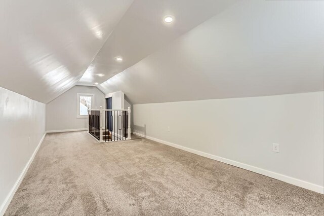 bonus room with lofted ceiling and light carpet