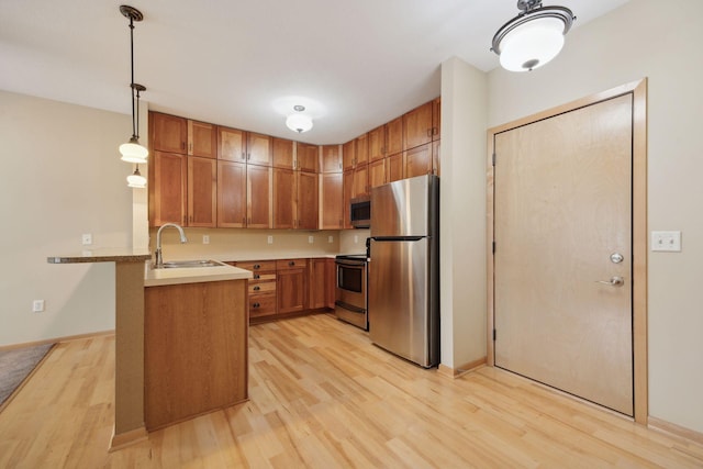 kitchen featuring a peninsula, light countertops, appliances with stainless steel finishes, brown cabinetry, and decorative light fixtures