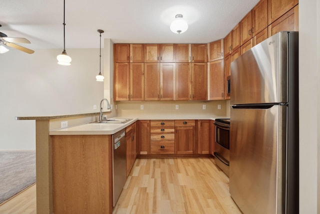 kitchen featuring a sink, stainless steel appliances, a peninsula, and light countertops