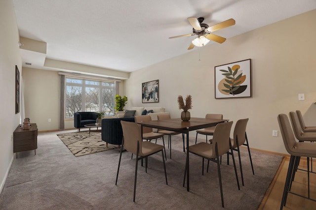 carpeted dining area featuring visible vents, baseboards, and a ceiling fan