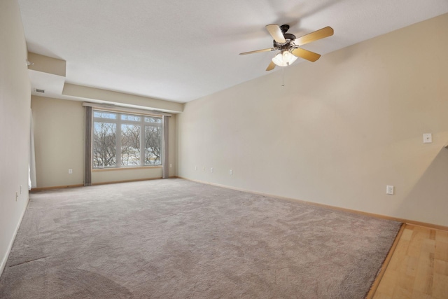 carpeted spare room featuring a ceiling fan, visible vents, and baseboards