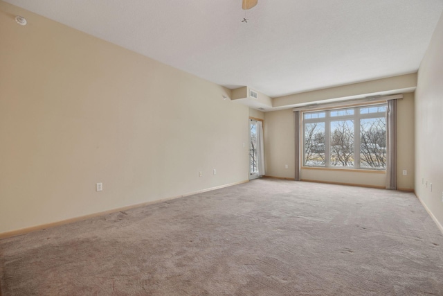 empty room with visible vents, baseboards, and light colored carpet