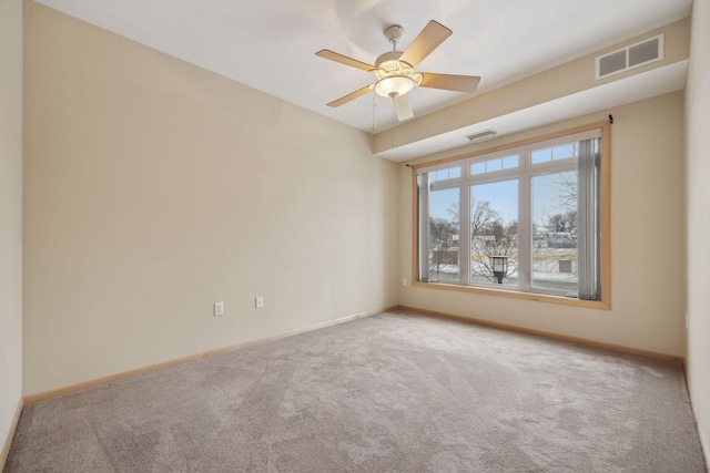 carpeted empty room featuring ceiling fan, visible vents, and baseboards