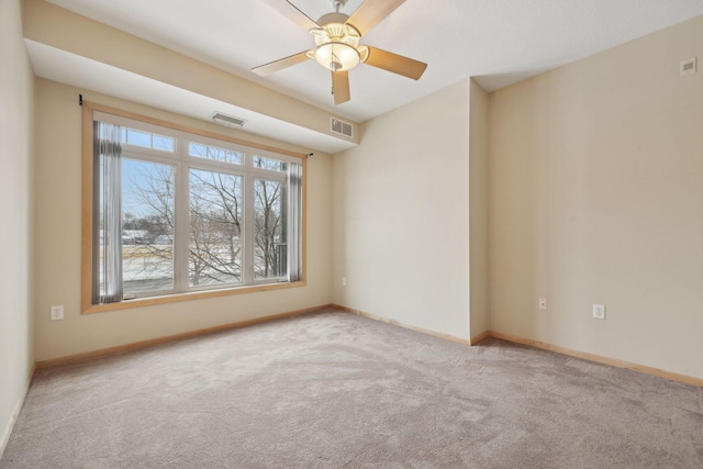 empty room featuring light carpet, a ceiling fan, visible vents, and baseboards