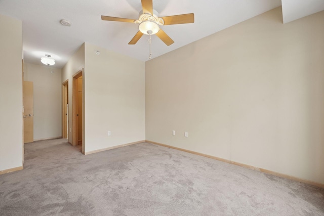 spare room with light carpet, ceiling fan, and baseboards