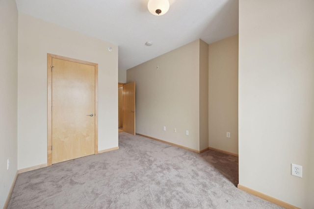 unfurnished room with light colored carpet and baseboards